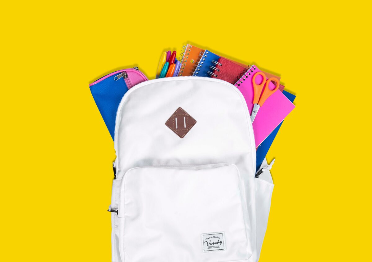 Fournitures scolaires colorées dans un cartable blanc, rentrée scolaire 2026